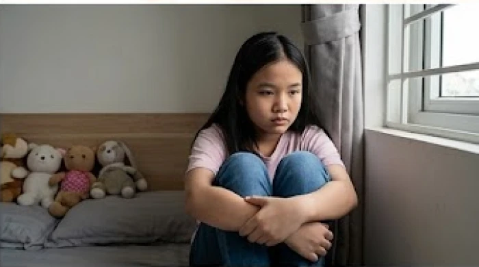 Bé gái ngồi lặng lẽ một mình ở góc phòng với vẻ mặt buồn bã khi phải chịu tổn thương về mặt cảm xúc
