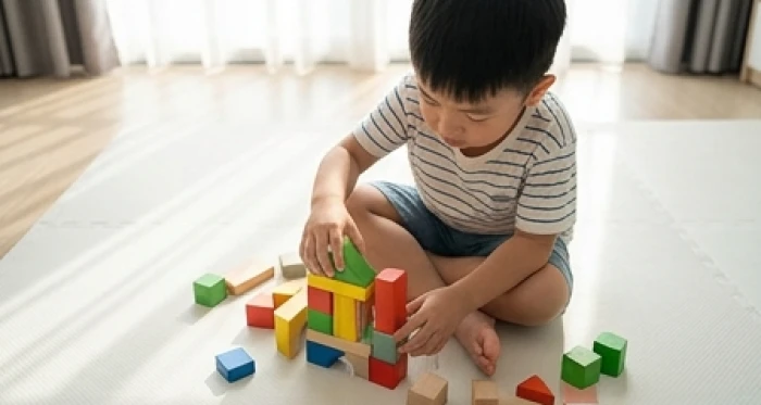 Bé trai cung Tốn say sưa tự tháo lắp khối xếp hình trên thảm trải sàn gỗ sạch sẽ