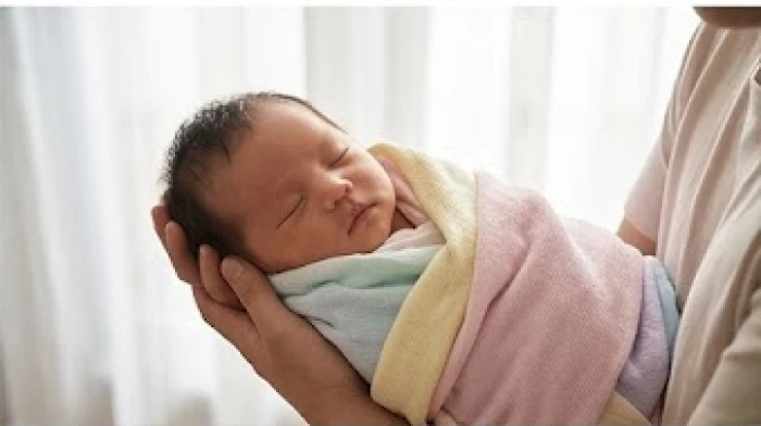 Em bé sơ sinh ngủ bình yên trong vòng tay ấm áp của bố mẹ mang lại sự gắn kết gia đình