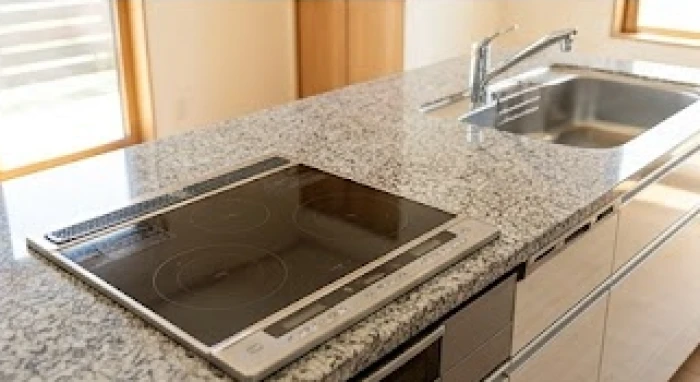 Gian bếp hiện đại với bếp từ và bồn rửa được bố trí cách xa nhau trên mặt bàn đá
