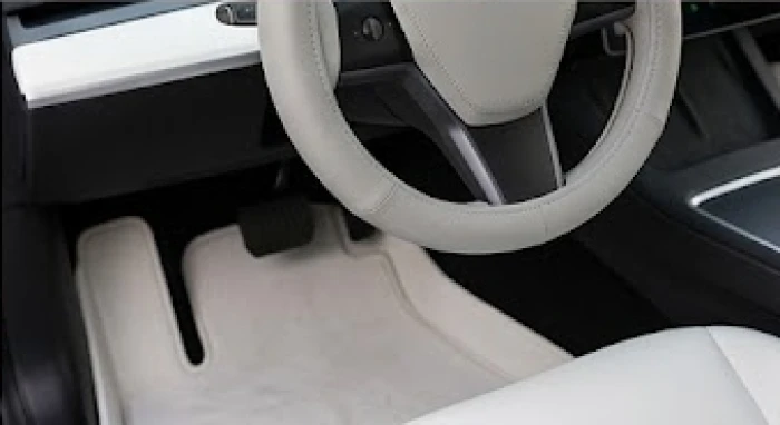 Vô lăng xe ô tô được bọc da màu xám ghi cao cấp cùng thảm trải sàn màu trắng sữa