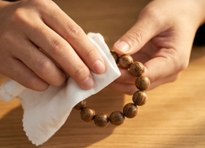 Đôi bàn tay dùng miếng vải cotton khô chà xát liên tục hạt gỗ trầm hương để phục hồi độ bóng sáng