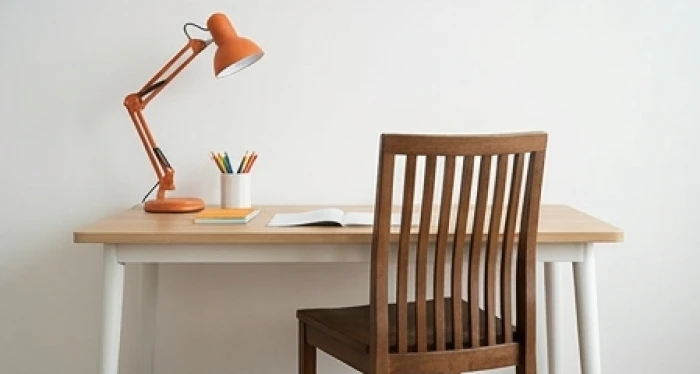 Bàn học với đèn màu cam góc trái và ghế tựa cao kê tựa sát vào bức tường vững chãi cho trẻ em