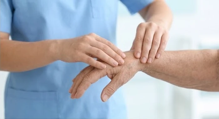 Bác sĩ đang nhẹ nhàng kiểm tra các khớp xương ở tay cho bệnh nhân trong phòng khám y tế