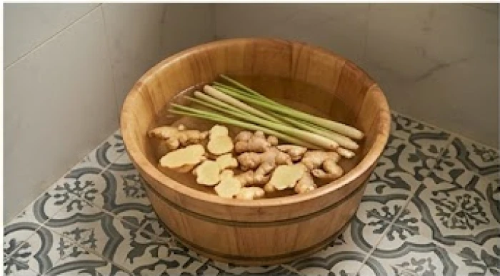 Chậu nước ấm pha gừng tươi và sả dùng để ngâm chân hoặc tắm giúp thư giãn cơ thể và tẩy trừ năng lượng xấu