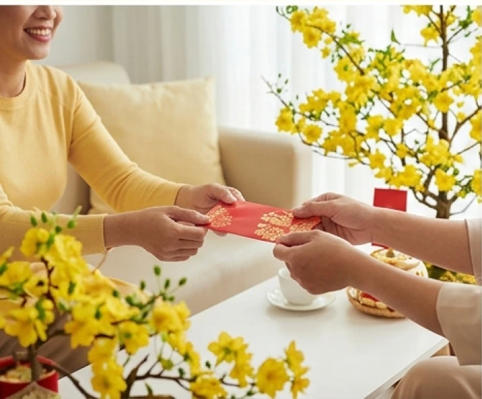 Khách quý hợp tuổi trao phong bao lì xì đỏ chúc tết gia chủ vào buổi sáng mùng một tết trong không gian ấm cúng