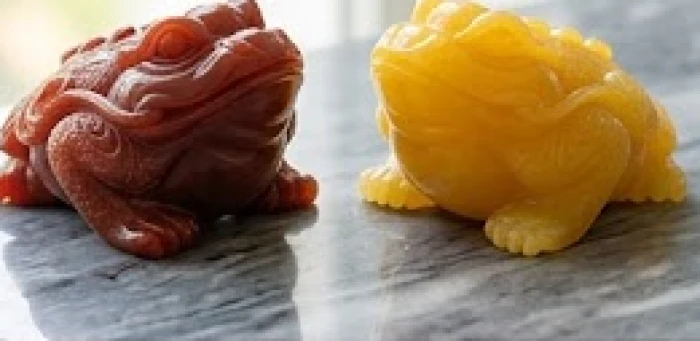 Hai mẫu tượng thiềm thừ chế tác từ đá mã não đỏ và ngọc hoàng long đặt cạnh nhau trên mặt bàn