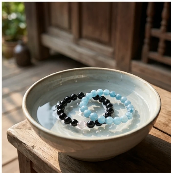 Vòng tay đá thạch anh đen cùng aquamarine tự nhiên được thanh tẩy cẩn thận trong chén nước muối bên hiên nhà