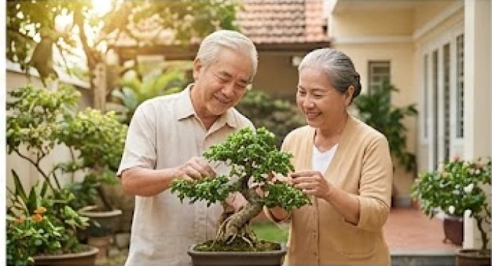 Vợ chồng lớn tuổi mỉm cười hạnh phúc khi cùng nhau chăm sóc cây kiểng trong sân nhà