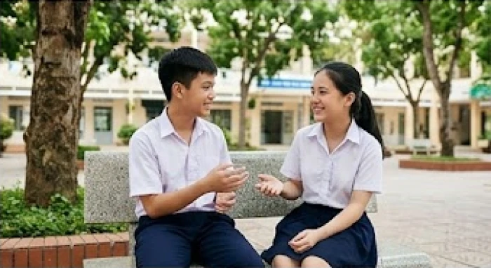 Hai học sinh trò chuyện thân thiện trên ghế đá sân trường trong giờ giải lao giữa các tiết học
