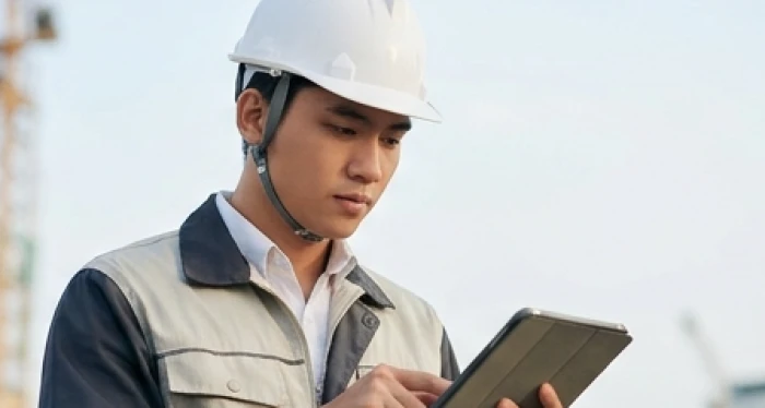 Kỹ sư giám sát thi công tuổi kỷ mão kiểm tra số liệu đo lường kỹ thuật trên công trường xây dựng