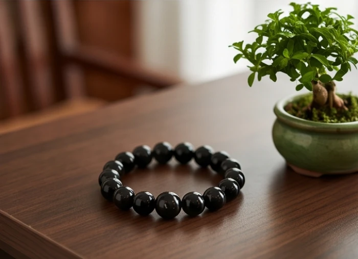 Vòng tay đá thạch anh đen tự nhiên cùng chậu bonsai nhỏ xanh mát trên bàn trà gỗ kích hoạt sinh khí bản mệnh