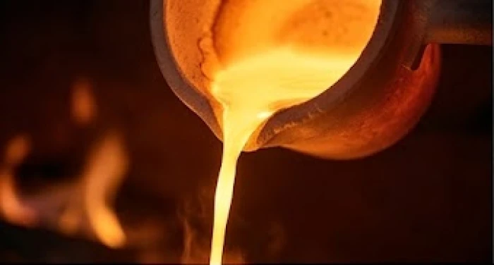 Dòng vàng nóng chảy lấp lánh phản chiếu ánh lửa đỏ rực trong quá trình tinh luyện quặng kim loại tự nhiên