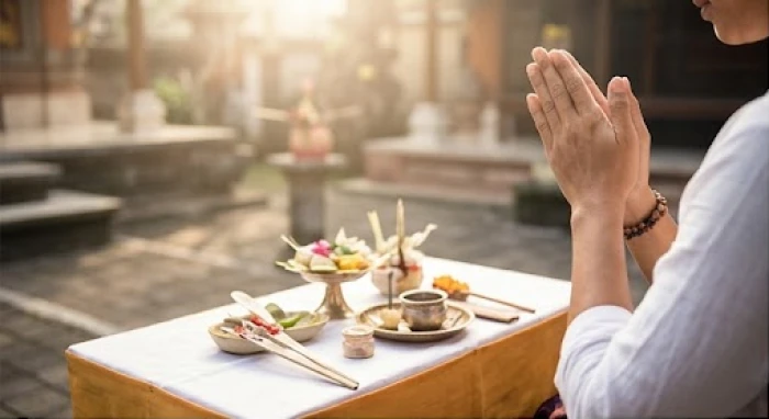 Người đàn ông chắp tay thành kính thực hiện nghi lễ khấn nguyện trước bàn cúng nhỏ đặt tại khoảng sân đầy nắng