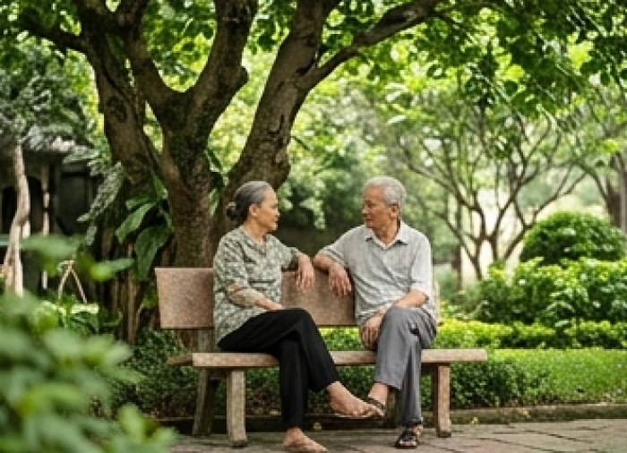 Hai người lớn tuổi đang ngồi thư giãn trên ghế đá dưới bóng cây mát mẻ