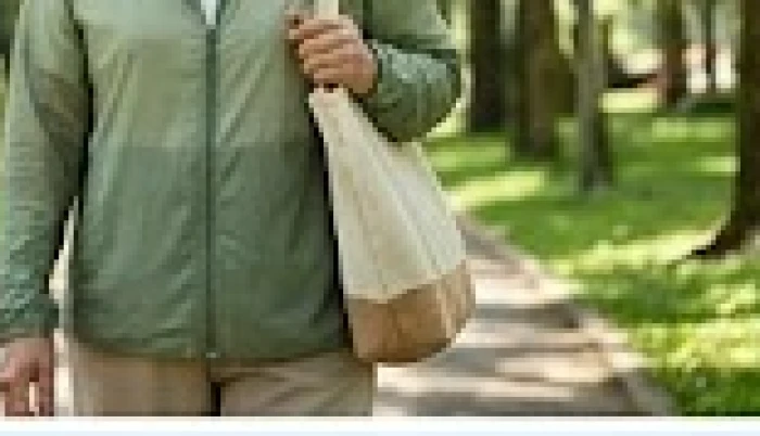 Bà cụ mặc áo khoác màu xanh lục đang thong thả đi dạo trong công viên rợp bóng cây