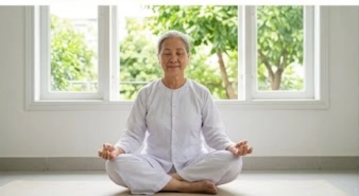 Cụ bà thư thái ngồi thiền tĩnh tâm trong không gian phòng khách ngập nắng