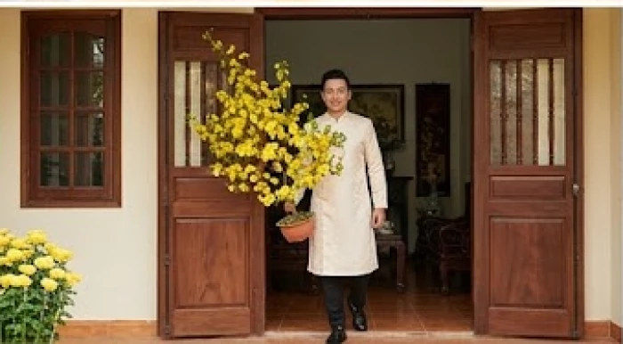 Người đàn ông trung niên mỉm cười bước vào cửa nhà mang theo cành mai vàng tươi tắn trong dịp Tết