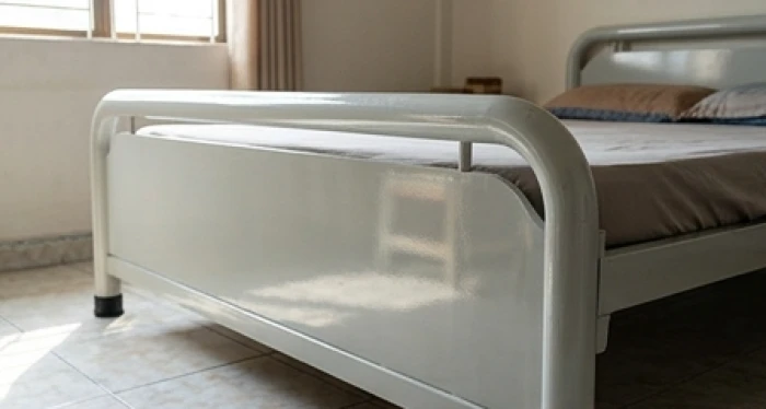Giường ngủ có chi tiết kim loại trắng sáng phản chiếu ánh sáng mạnh