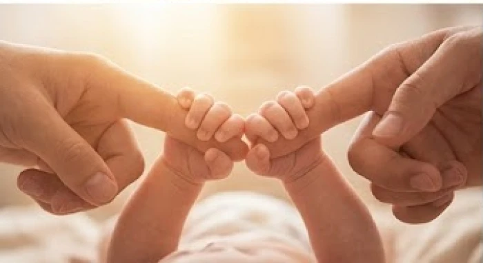 Em bé đang nắm lấy ngón tay của bố mẹ thể hiện sự gắn kết và hóa giải xung khắc trong gia đình