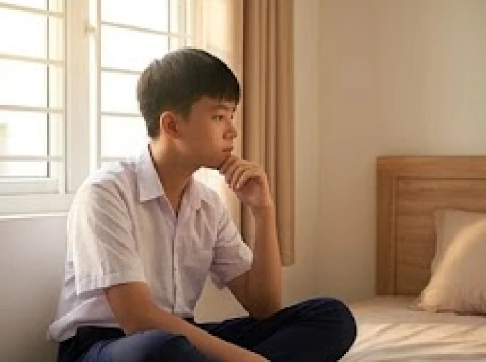 Thiếu niên 14 tuổi trầm ngâm bên bàn học cần được cha mẹ quan tâm và lắng nghe thấu hiểu