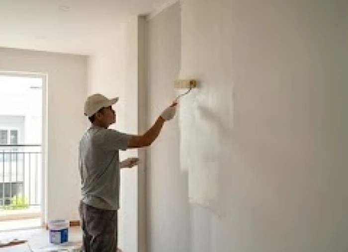 Người thợ đang cẩn thận dùng rulo lăn lớp sơn mới lên bức tường phòng khách để tân trang lại không gian