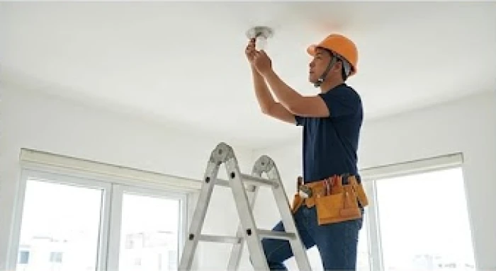 Thợ điện nước chuyên nghiệp đang thi công lắp đặt thiết bị trên thang cao thay vì để gia chủ tự làm
