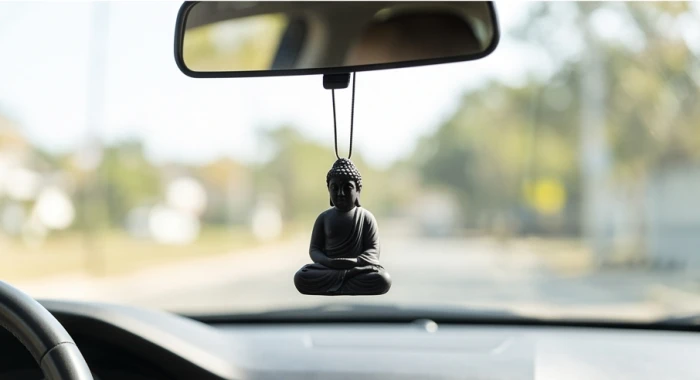 Tượng Phật bình an màu đen nhám được treo trang trọng trên gương chiếu hậu bên trong không gian nội thất xe ô tô