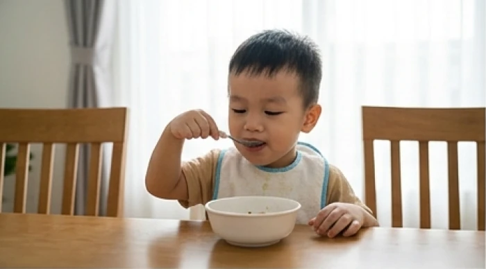 Bé trai tuổi Nhâm Dần 2022 tự xúc ăn và đi giày một cách chăm chú trong không gian phòng ăn gia đình