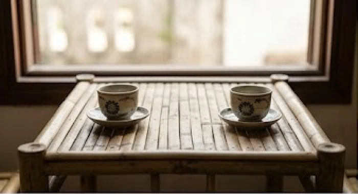 Hai tách trà gốm sứ đặt đối diện nhau trên bàn tre thể hiện các hướng trực xung trong tứ hành xung dần thân.