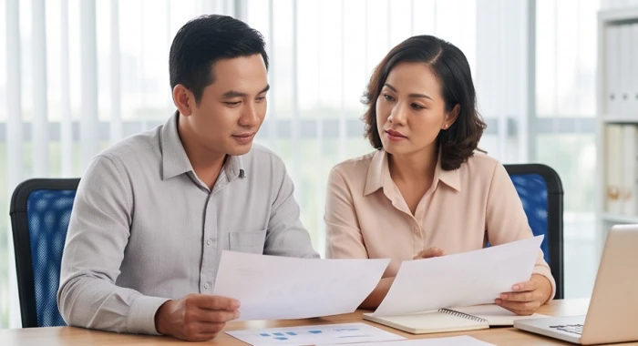 Hai đối tác kinh doanh trao đổi tài liệu thảo luận dự án trong phòng làm việc hiện đại ấm cúng