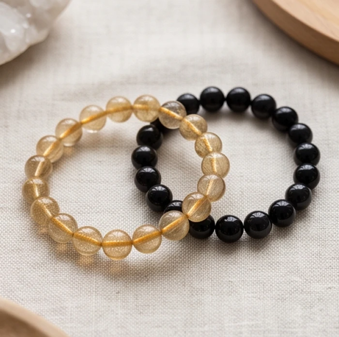 Hai chuỗi vòng tay đá thạch anh tóc vàng và đá obsidian đen nhánh đại diện cho hai mệnh kim và thủy