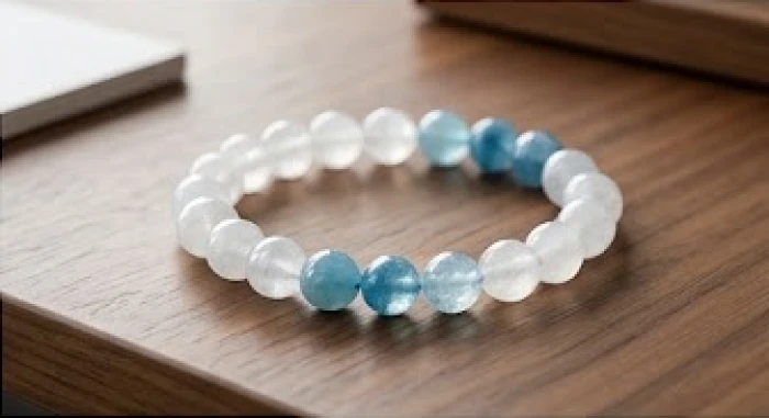 Vòng tay đá thạch anh trắng và hạt đá xanh dương tự nhiên đặt trên mặt bàn gỗ thanh lịch