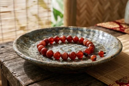 Cận cảnh chiếc vòng tay phong thủy tuổi tuất làm từ đá mã não đỏ đặt trên đĩa gốm sứ truyền thống