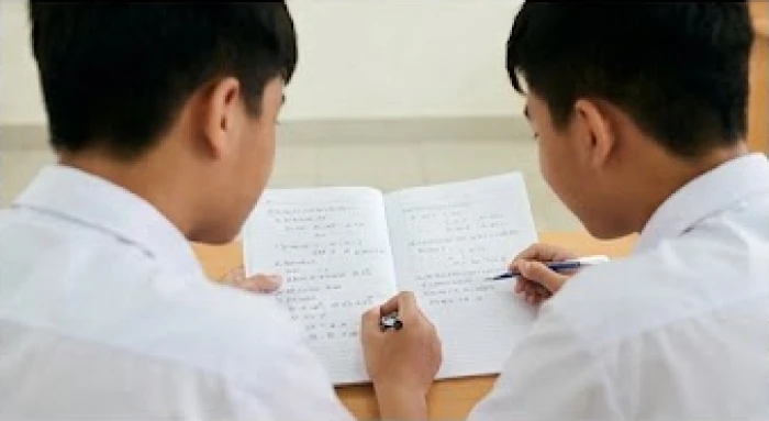 Học sinh kiên nhẫn giải thích ý tưởng trên trang giấy cho bạn cùng nhóm đang có ý kiến trái chiều
